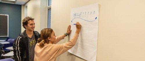 鶹ƵAPP students writing help on a poster